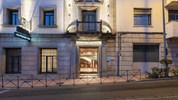 A hotel entrance with a balcony, a sign reading 'Alfonso VIII', and a gated entrance.