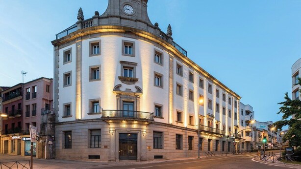 A historic building with a clock tower, multiple balconies, and a classic architectural style. - Dorma Alfonso VIII (Plasencia)