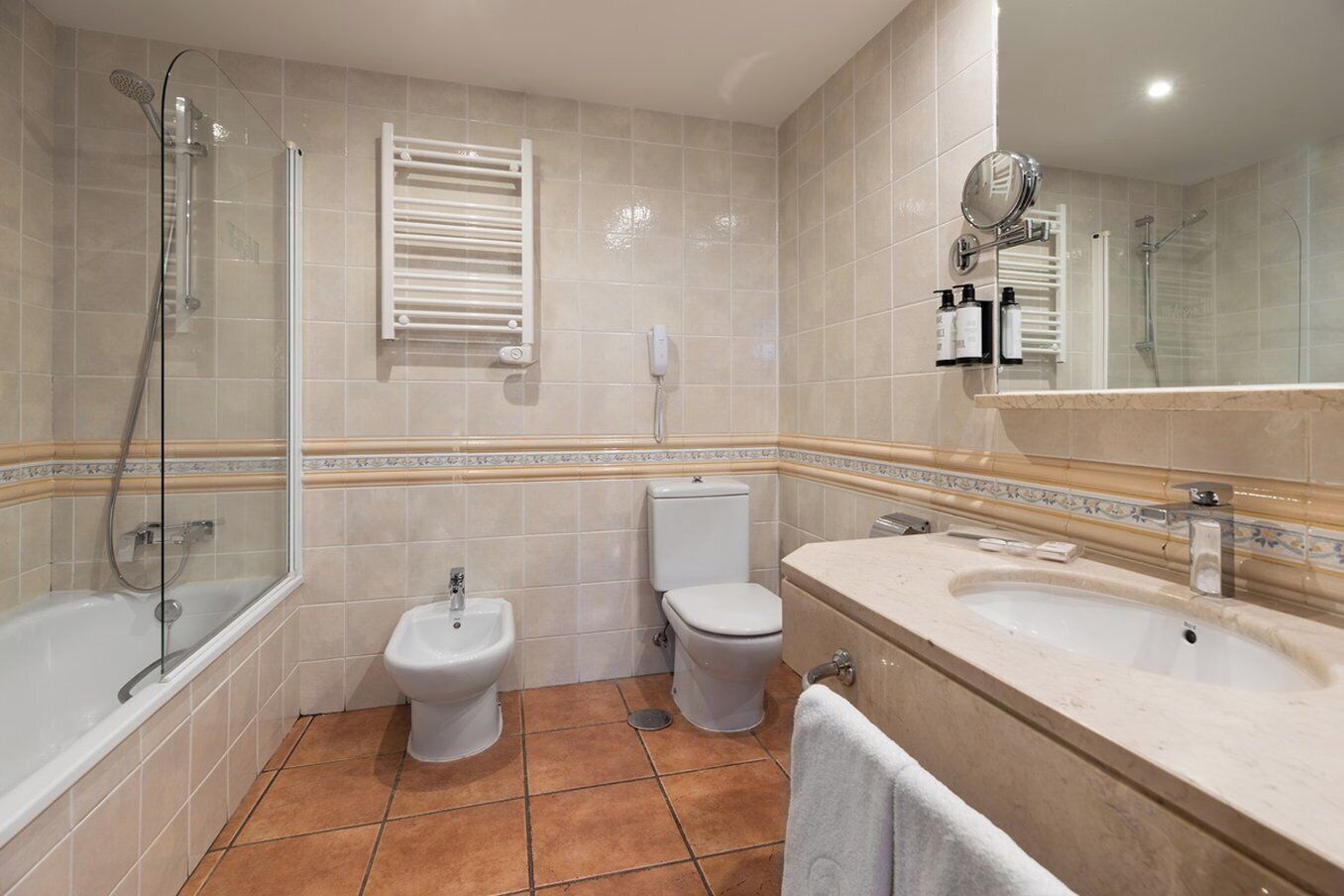A bathroom with a bathtub, a shower, a bidet, a toilet, and a sink with a mirror.