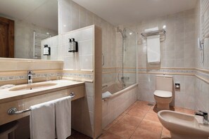 Un baño moderno con lavamanos, inodoro, bidé y ducha con mampara de vidrio.