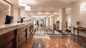 A hotel lobby with a reception desk, check-in counters, a staircase, and a dining area. - Dorma Alfonso VIII (Plasencia)