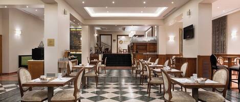A hotel dining area with checkered flooring, wooden tables, and chairs.