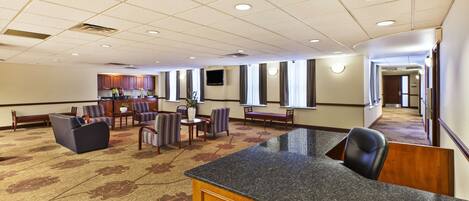 A hotel lobby with a reception desk, seating area, and a bar.