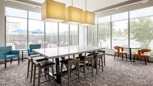 Une salle de conférence dotée d’une grande table et de chaises, de larges fenêtres offrant une vue sur l’extérieur et d’un tapis à motifs.