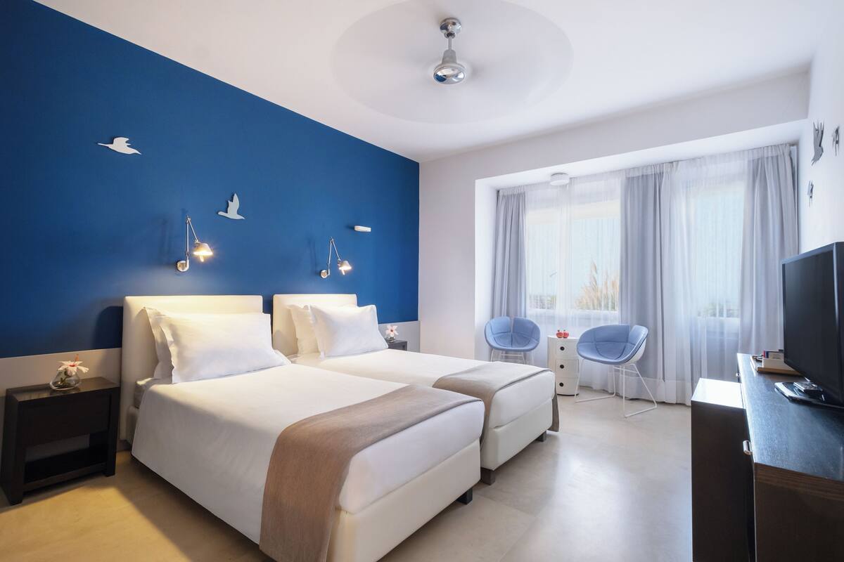 Une chambre d’hôtel avec deux lits, une télévision, un bureau et une chaise.