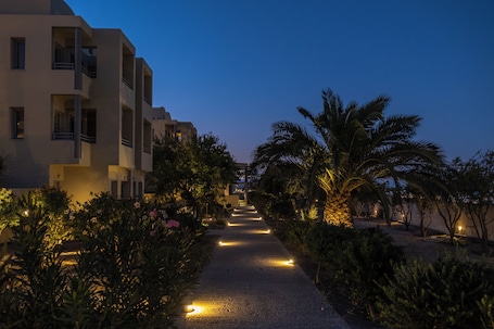 A pathway flanked by palm trees and buildings with balconies, leading towards a building entrance.. The Majestic Hotel