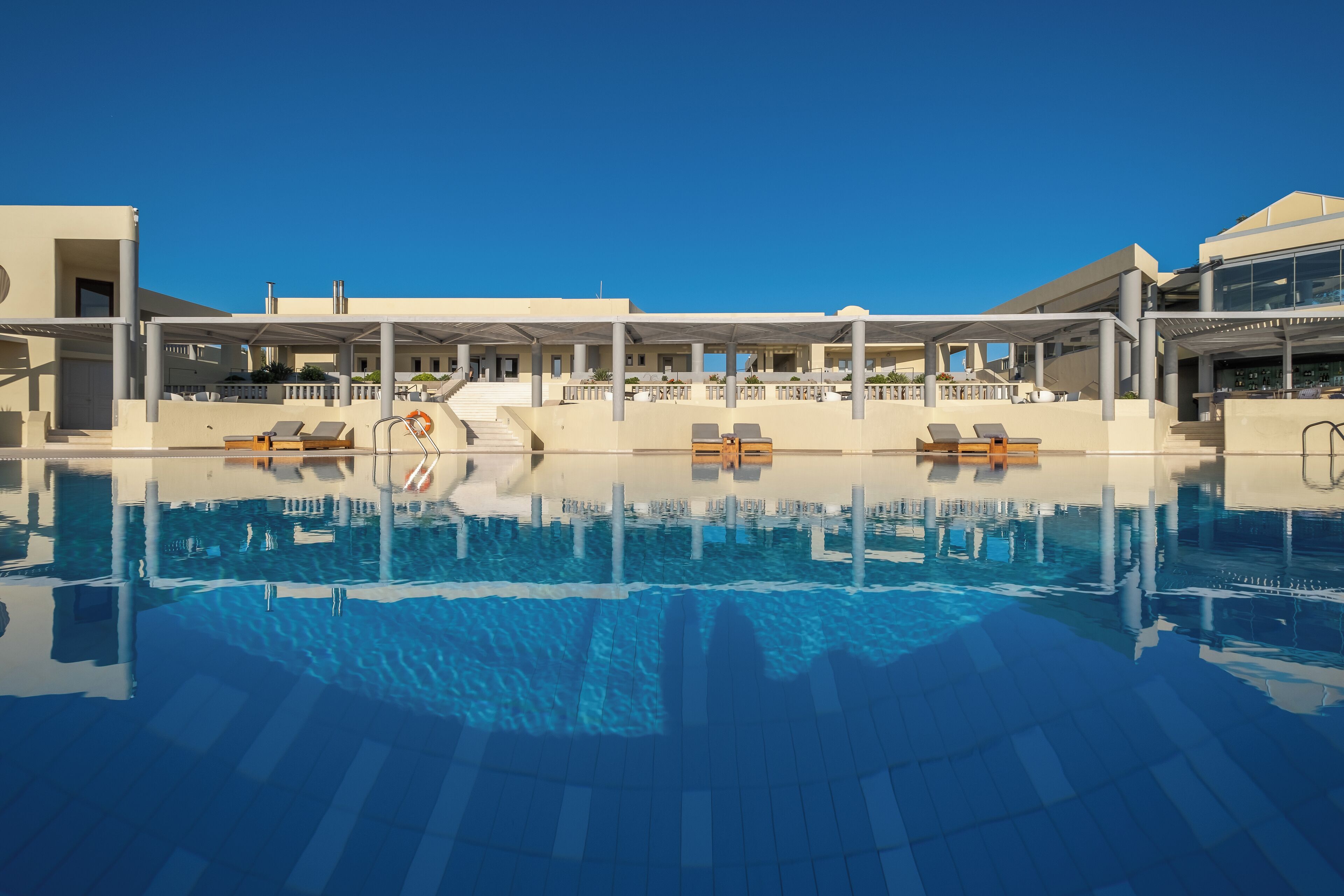A swimming pool with lounge chairs and a covered area with stairs leading to a building.