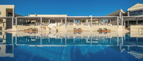 A swimming pool with lounge chairs and a covered area with stairs leading to a building.
