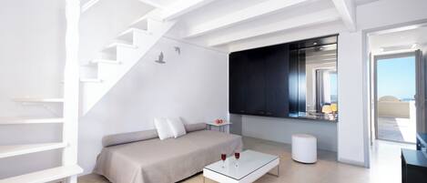 A modern living room with a staircase, a sofa, a coffee table, and a view of the outdoors.