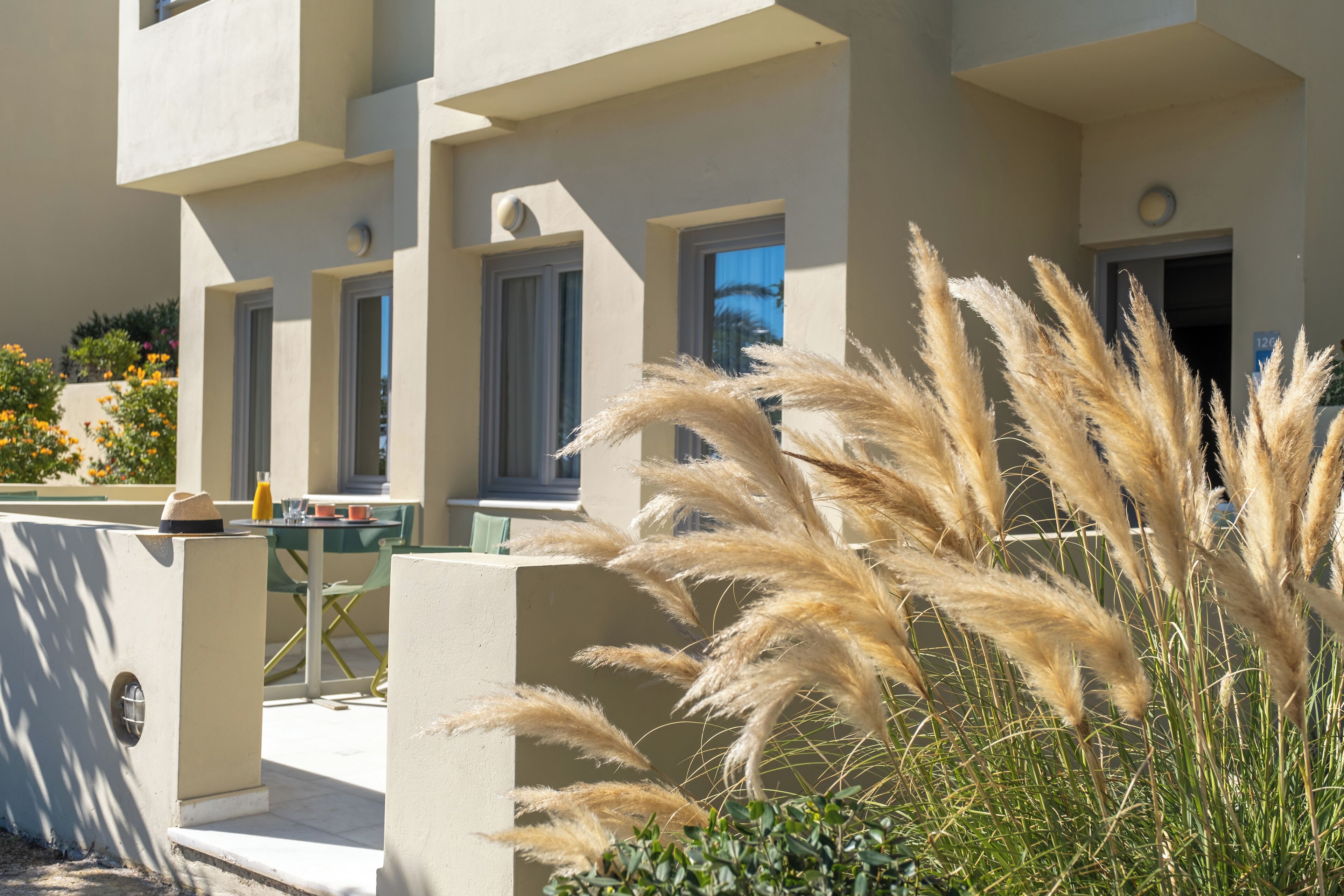 A modern building with a flat facade, large windows, and a patio area with outdoor seating.