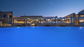 A modern hotel with a swimming pool, outdoor seating, and a covered area.