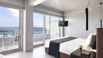 Une chambre d’hôtel moderne dotée d’un grand lit, d’une télévision et d’un balcon offrant une vue sur la mer.