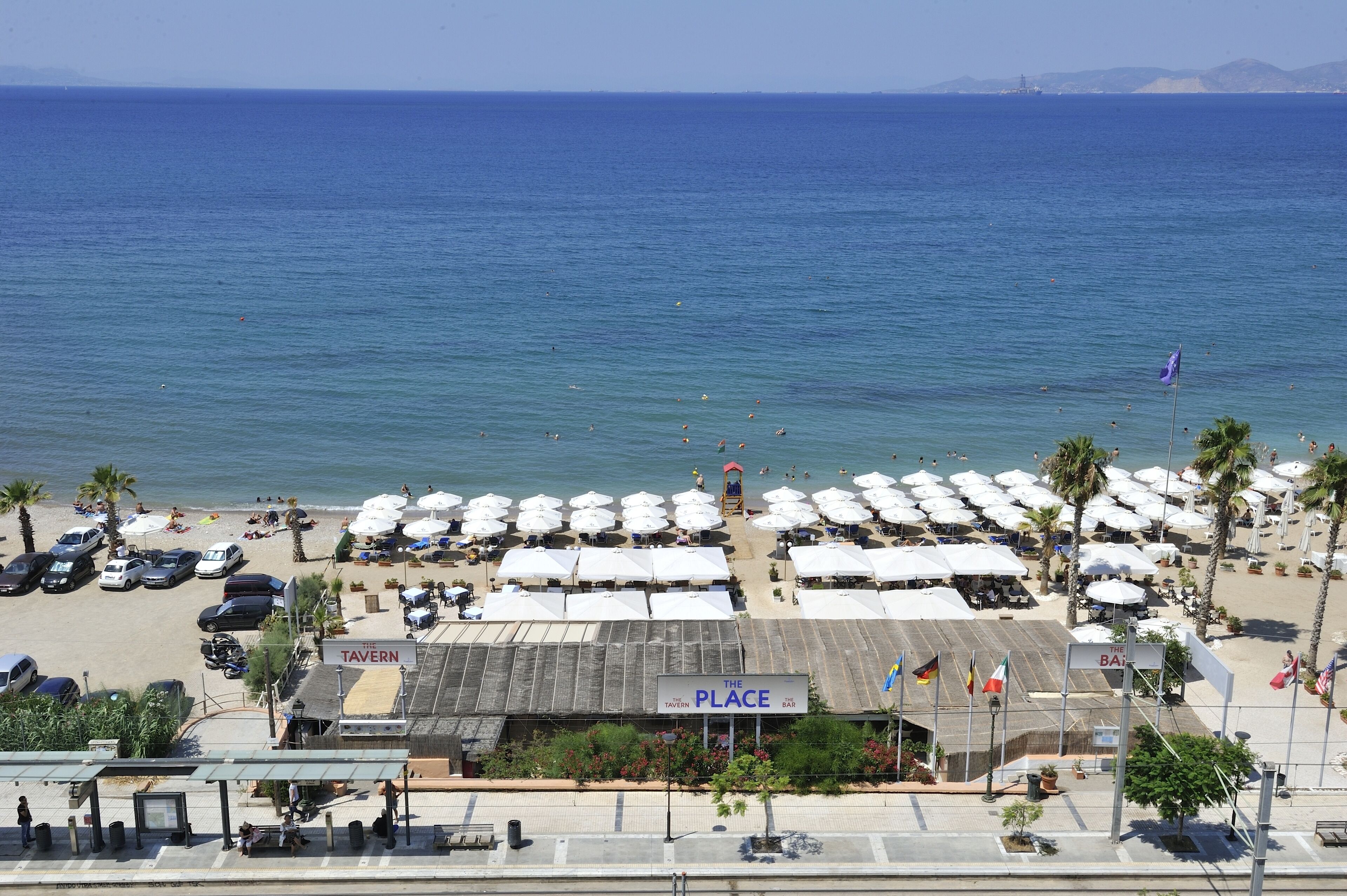 Un restaurant situé en bord de mer, avec une terrasse et des parasols, un parking et une vue sur la mer.