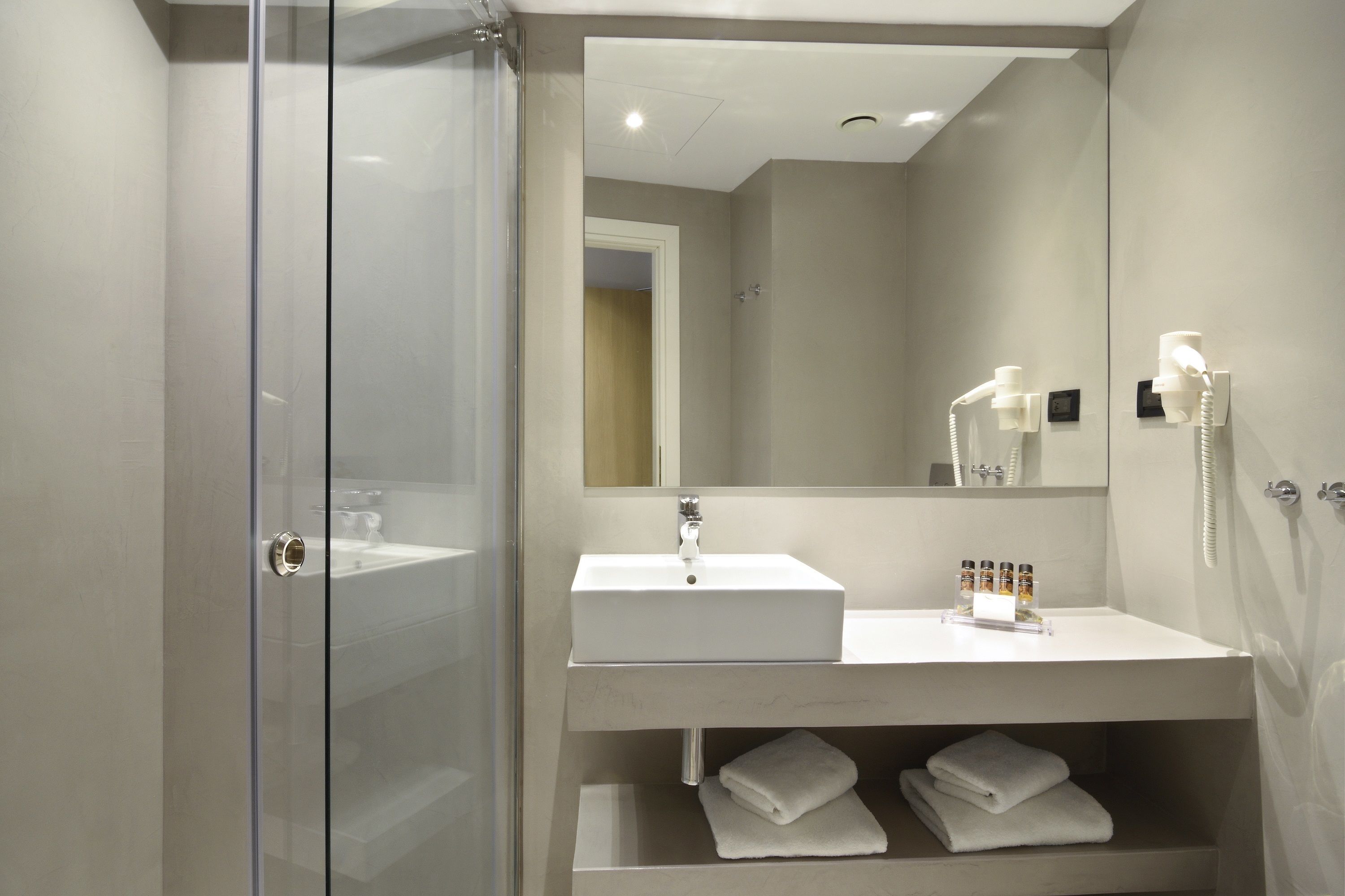 Une salle de bain moderne avec une douche à parois de verre, un lavabo blanc et un miroir au-dessus.