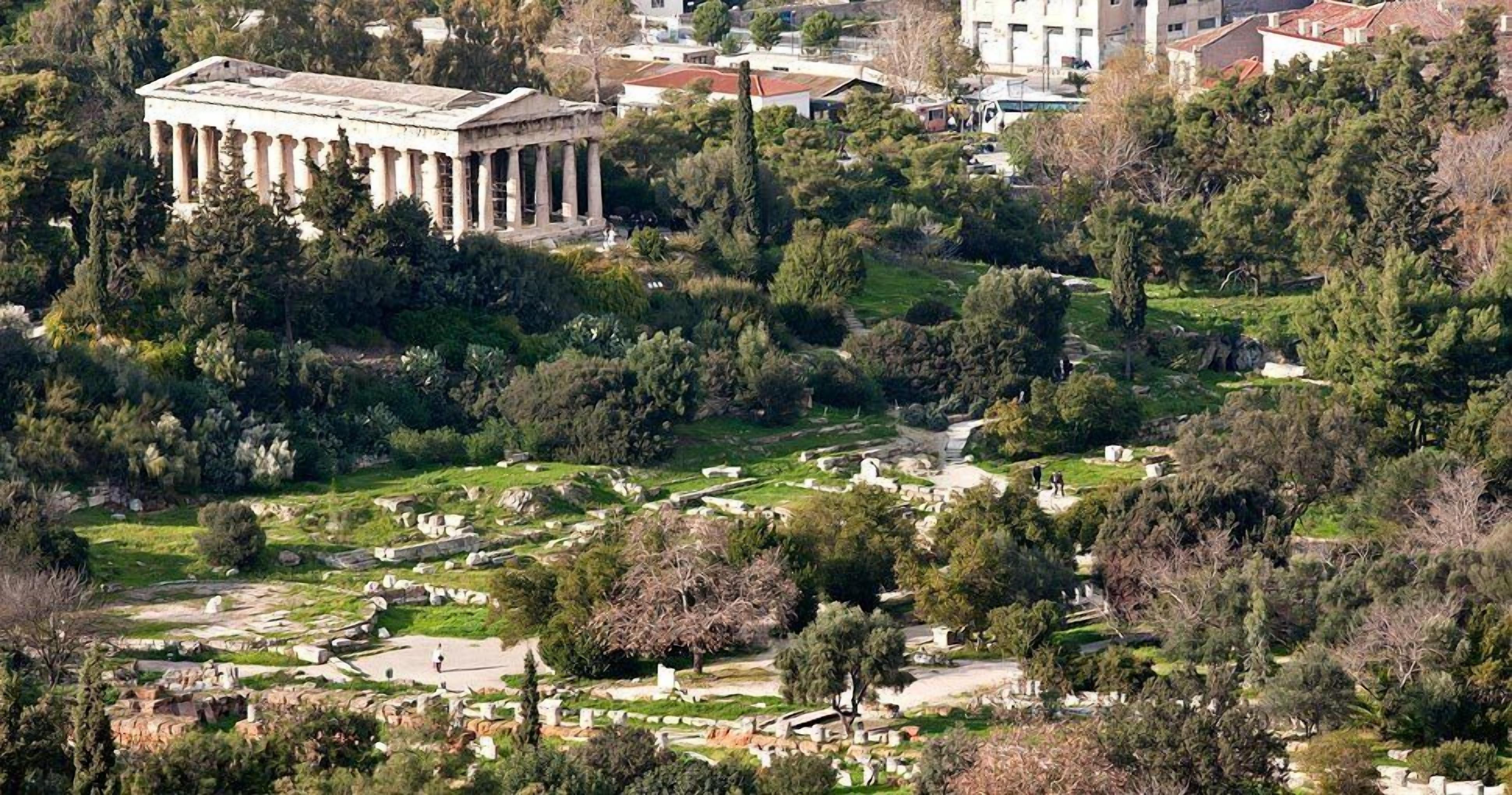 Un ancien temple grec entouré d’un cimetière où se trouvent des tombes et des arbres.