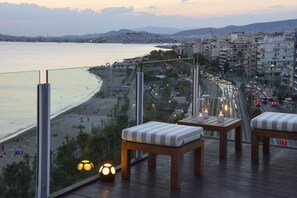 Un balcón con muebles de madera y vistas a la playa y al paisaje urbano.