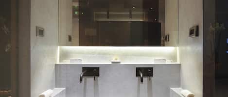 A modern bathroom with a large mirror, two sinks, and a towel rack.