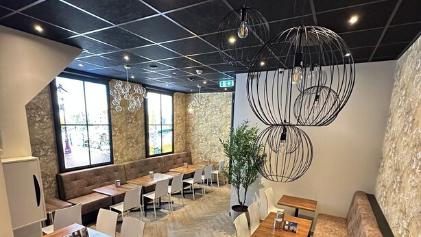 A modern restaurant with a mix of seating options, including tables and booths, and a large window offering a view.