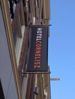 Ein schwarzer Banner mit der Aufschrift "HOTEL CORNELISZ" in weißer und orangefarbener Schrift.
