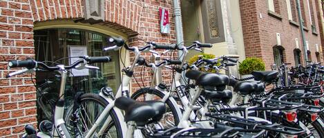 A row of bicycles parked in front of a hotel with a brick facade and a sign that reads "HOTEL".
