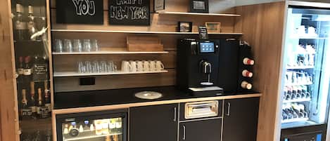 A bar area with shelves of bottles, glasses, and a coffee machine.