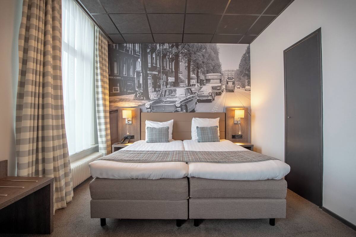 A double bed with two pillows, a nightstand, and a lamp.