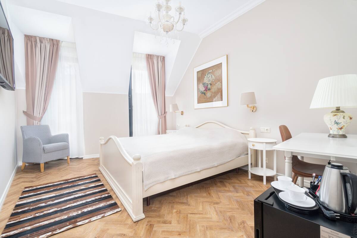 Hotellihuone, jossa on sänky, työpöytä, tuoli, kahvinkeitin ja taulu seinällä.
