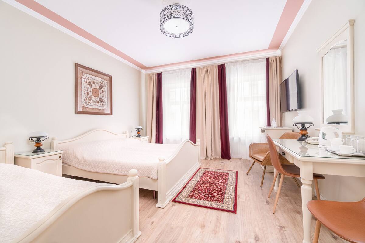 Hotellihuone, jossa on sänky, yöpöytä, tuoli, työpöytä ja televisio.