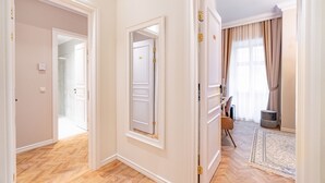 Un pasillo con suelo de madera, paredes blancas y una puerta que da a otra habitación.