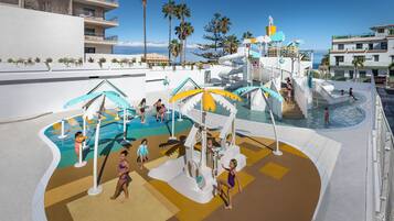 Een waterpark met glijbanen en zwembaden, omgeven door palmbomen en gebouwen.