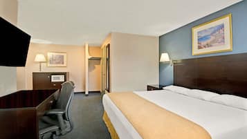 A hotel room with a bed, desk, chair, and a television.
