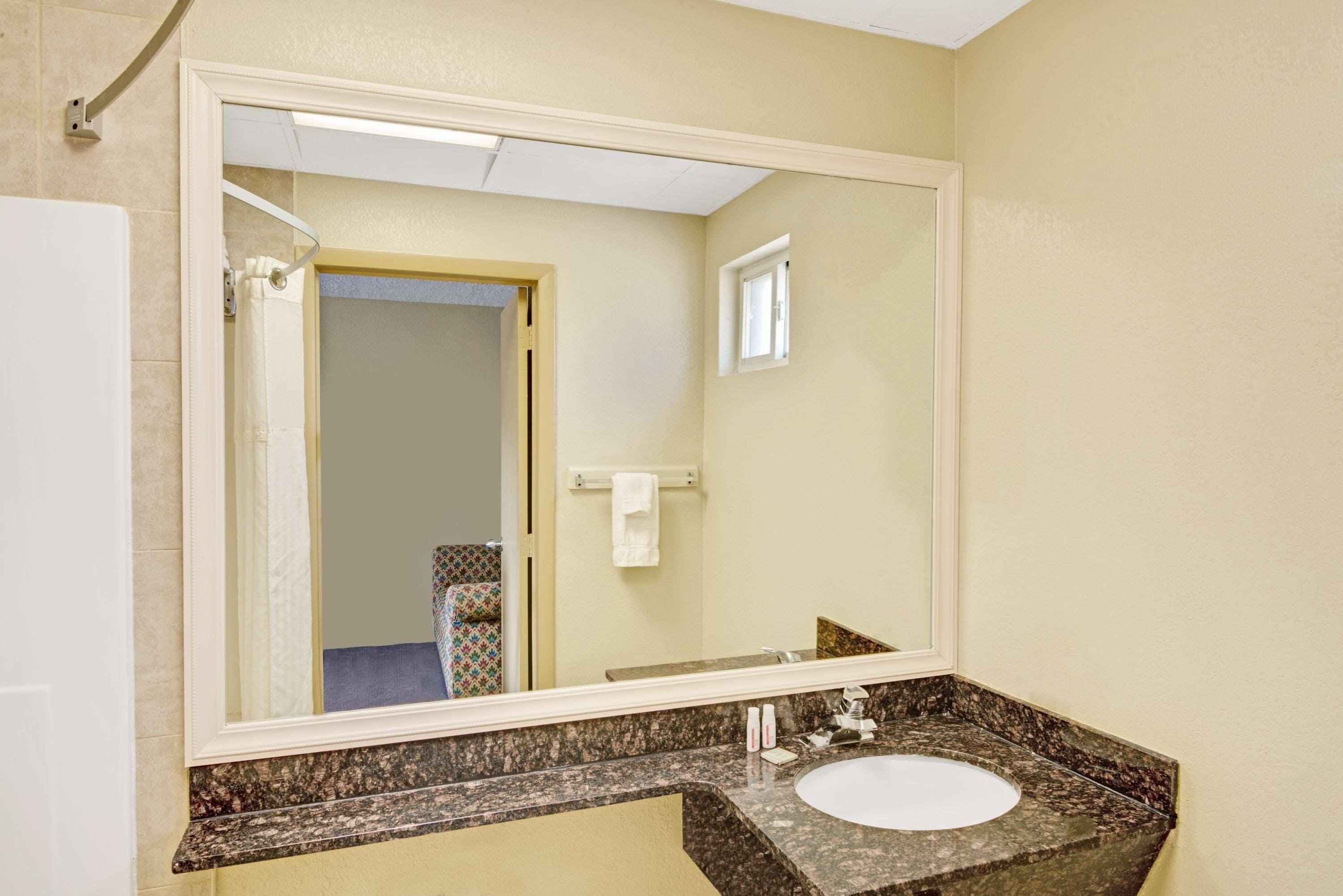 Un baño con un espejo grande, un lavabo y un perchero para toallas.