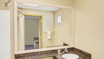 Un baño con un espejo grande, un lavabo y un perchero para toallas.
