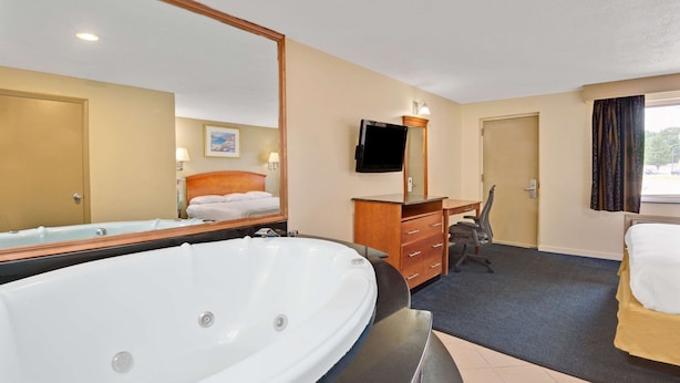 Habitación de hotel con una bañera grande, un escritorio con silla, televisión y cama.