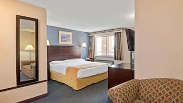 A hotel room with a bed, a chair, a desk, a mirror, a window with curtains, and a painting on the wall.