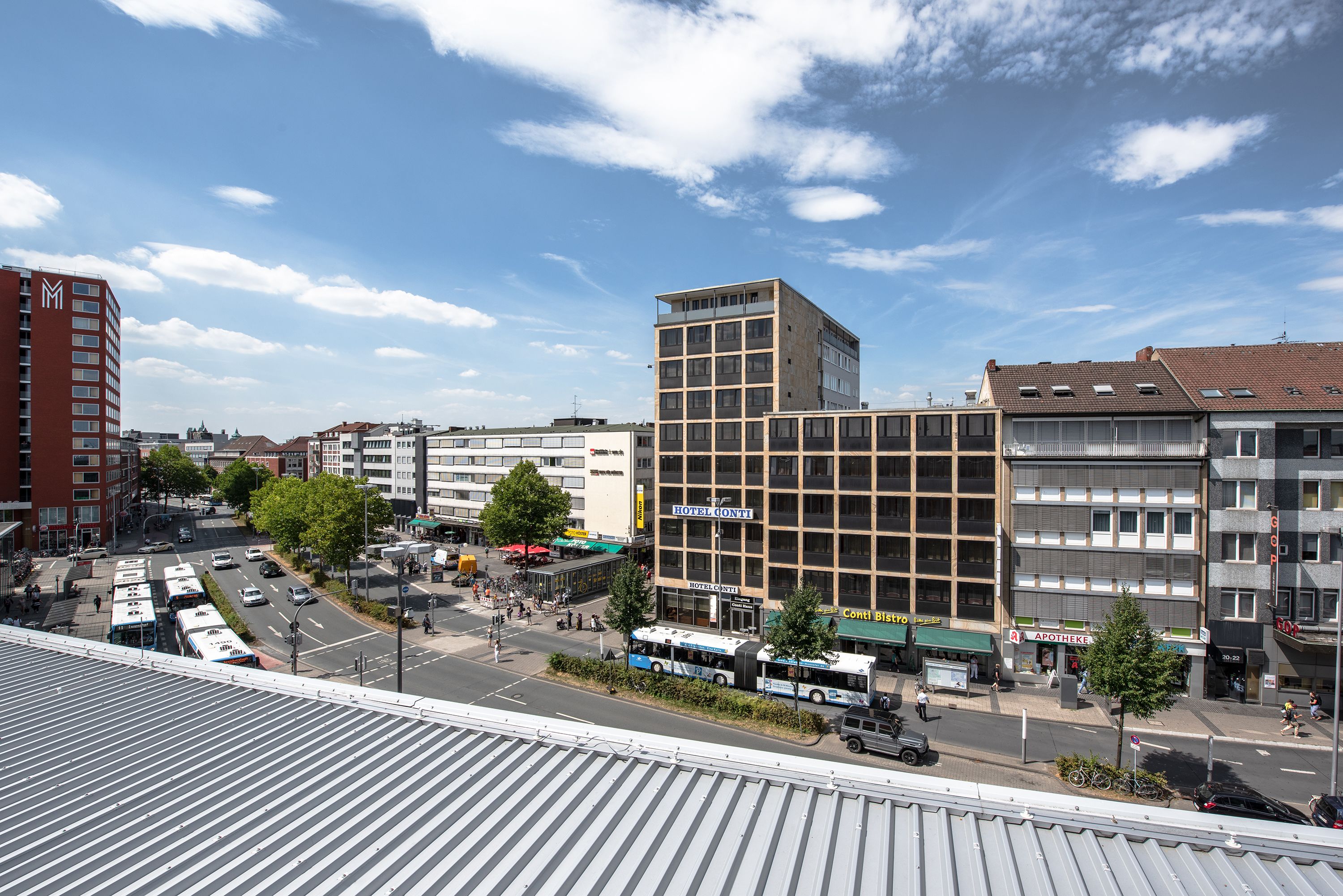 Un hôtel au design moderne, avec plusieurs étages et une enseigne bien visible indiquant « HÔTEL CONTI ».