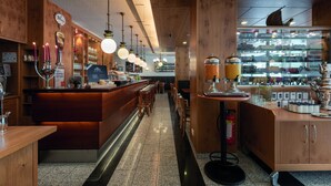 Un bar moderne avec des éléments décoratifs en bois, un long comptoir et des luminaires suspendus.