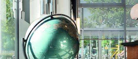 A globe on a stand in a modern room with a red sofa and a large window.