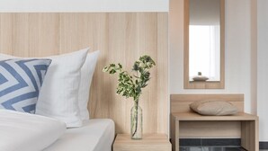 Une chambre à coucher moderne avec un lit, une table de chevet, un vase de fleurs et un miroir.