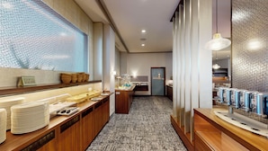 Un hall d’hôtel comprenant un espace buffet, un comptoir d’accueil et un coin salon avec une moquette à motifs.