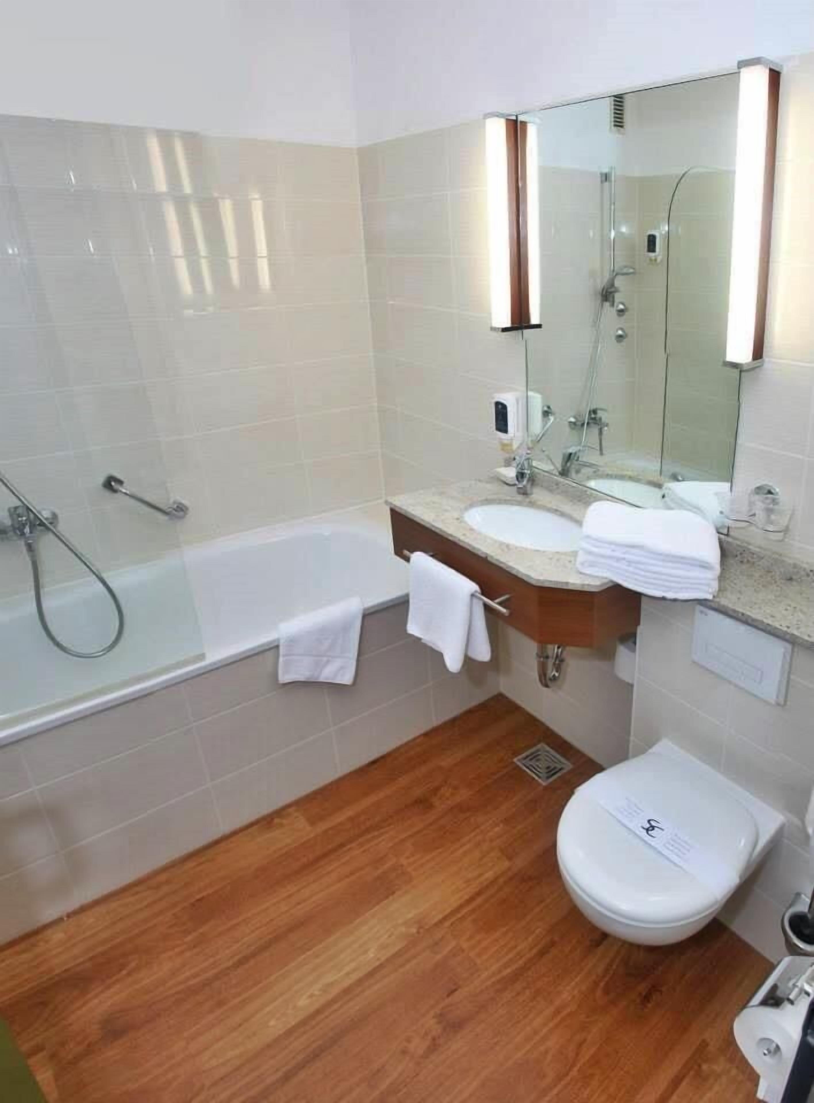 A modern bathroom with a glass-enclosed shower, a sink with a mirror, and a toilet.