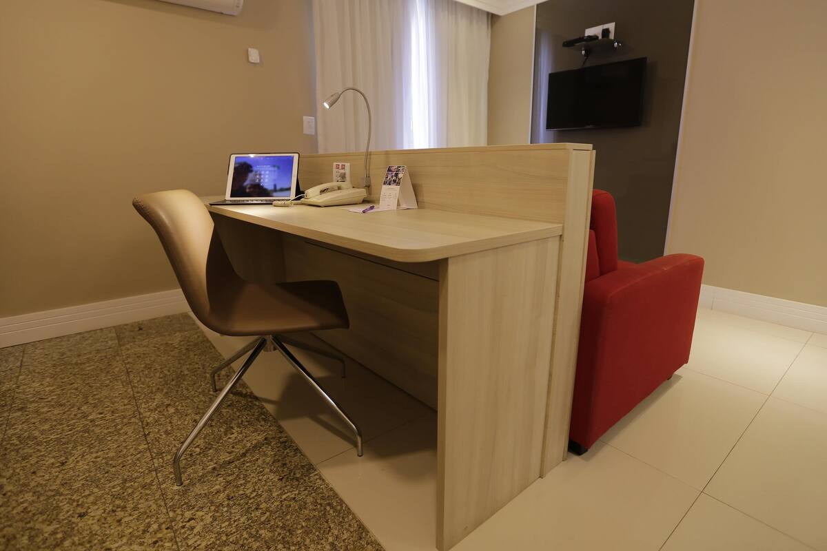 Un pequeño espacio de oficina con un escritorio, una silla y un sillón rojo.