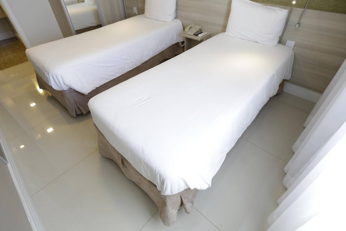 Habitación de hotel con dos camas, un teléfono en la mesita de noche y una lámpara.