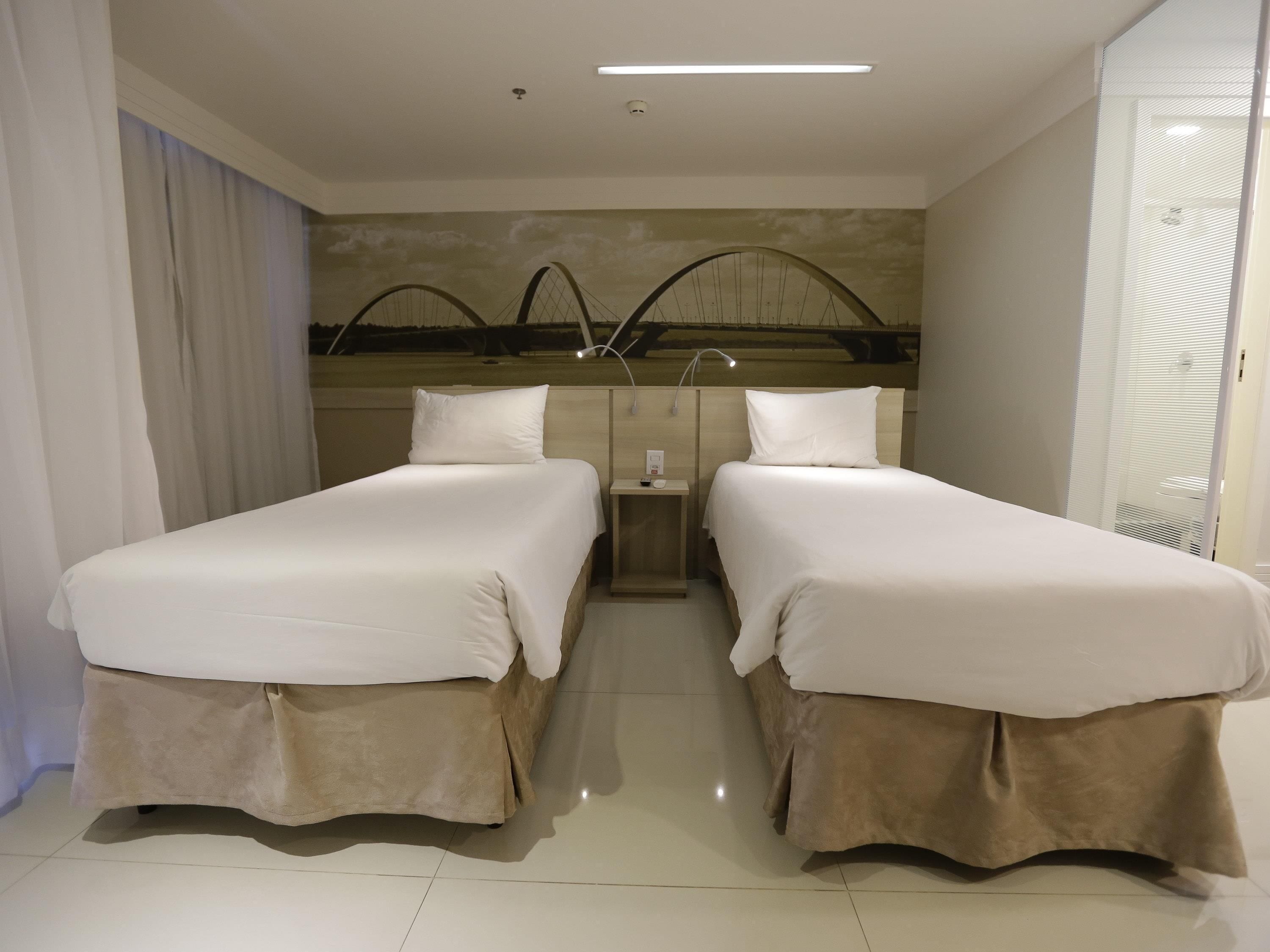Une chambre d’hôtel avec deux lits, une table de chevet et un miroir.