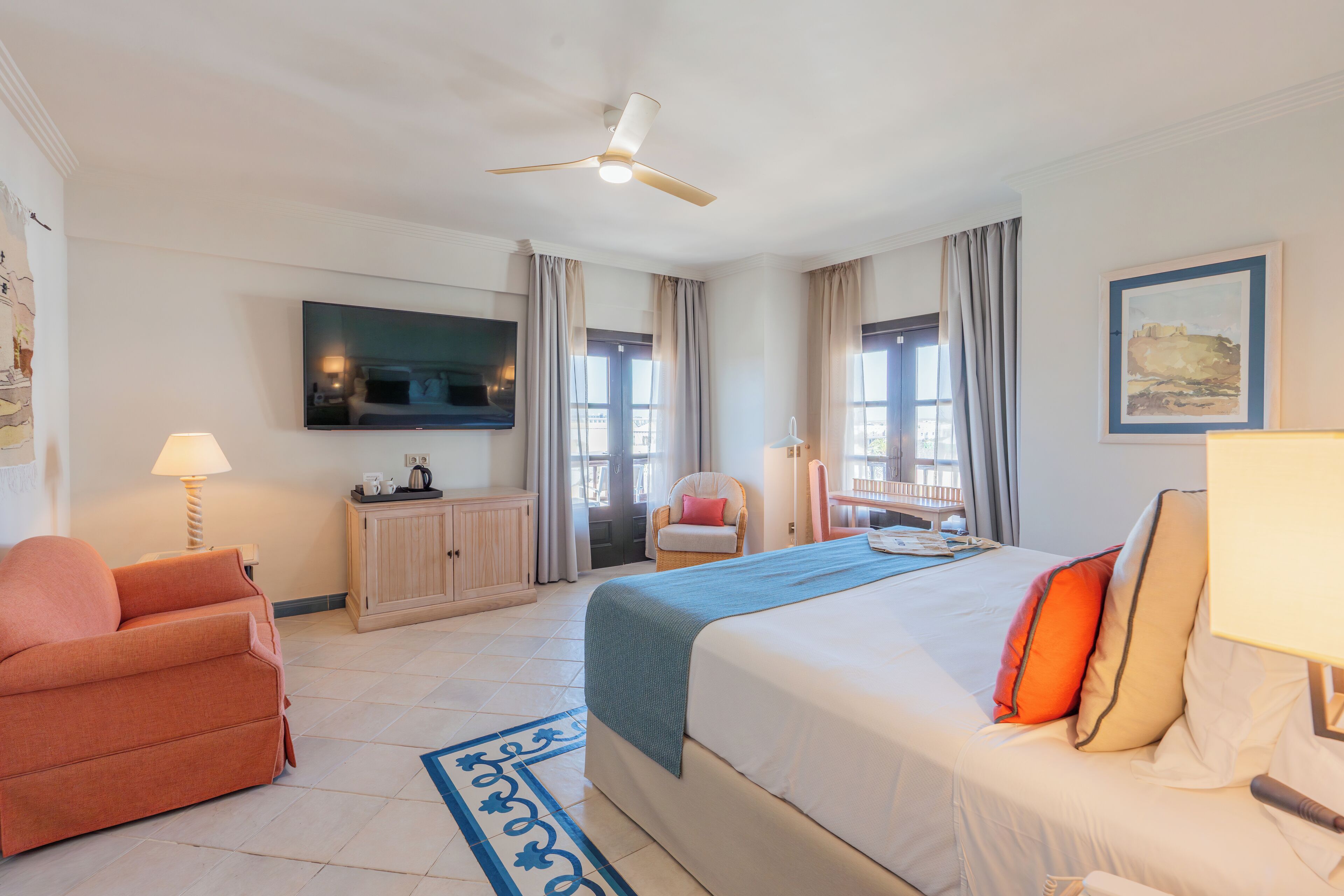 Een hotelkamer met een bed, televisie, bureau, stoel en raam.