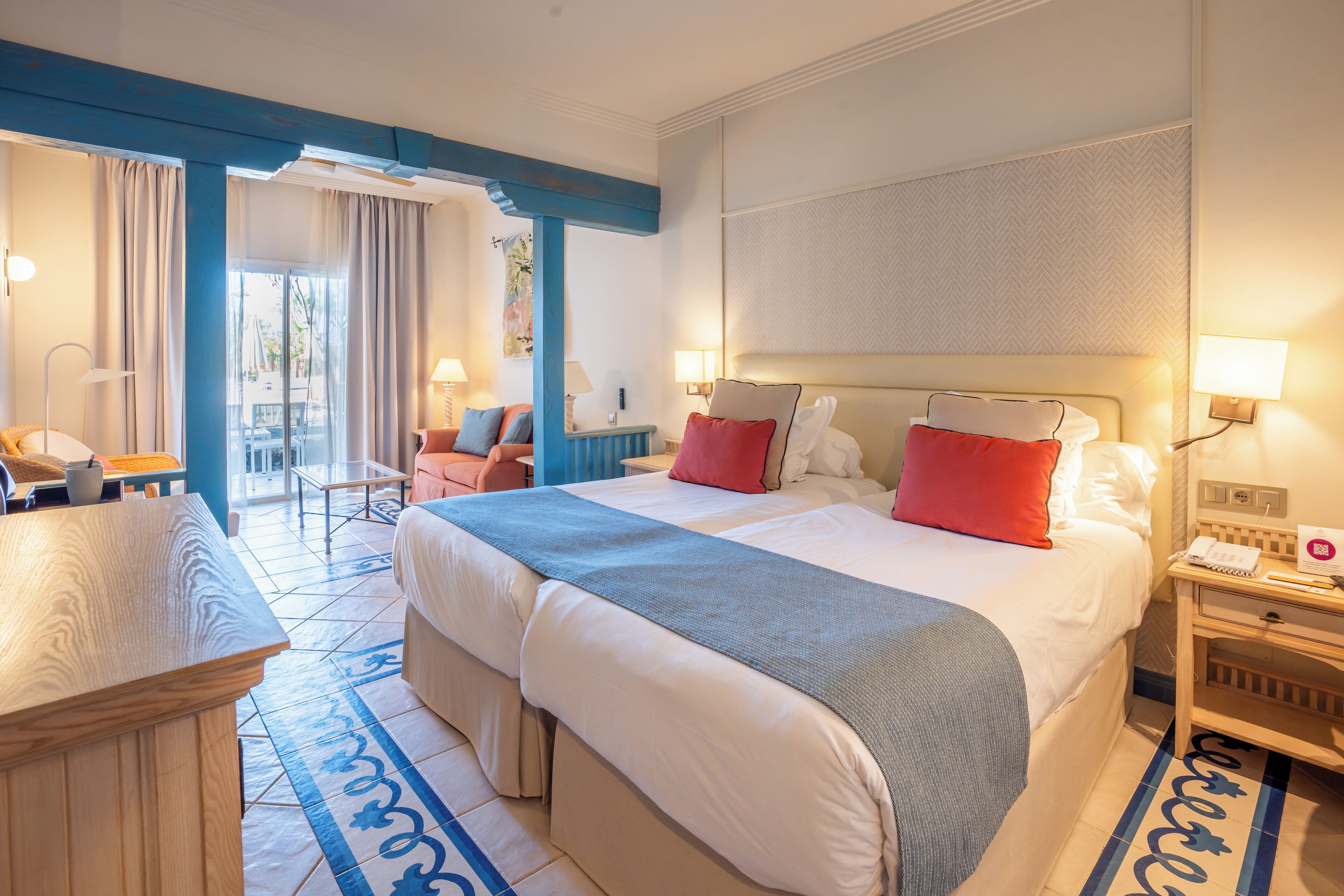 A hotel room with a large bed, two bedside tables, a desk, and a chair.