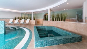 A modern indoor swimming pool with a curved design, lounge chairs, and potted plants. - Hotel LIVVO Volcán Lanzarote (Yaiza)