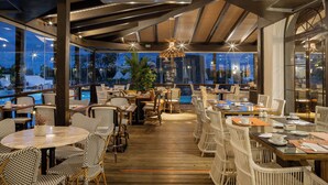 An outdoor dining area with wicker furniture and a view of the pool. - Hotel LIVVO Volcán Lanzarote (Yaiza)