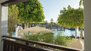 A poolside view with a bridge, lounge chairs, and umbrellas. - Hotel LIVVO Volcán Lanzarote (Yaiza)