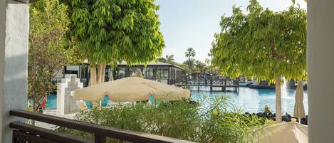 A poolside view with a bridge, lounge chairs, and umbrellas.